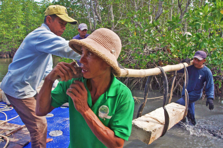 Trapang Ropov community members load a concrete pillar onto a raft.