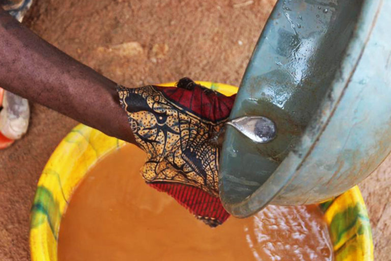 A miner panning for gold in a gold-bearing basin using mercury