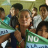 At an assembly, the president of the Shuar Arutam People shows banners saying “No to mining.”