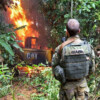 IBAMA officers watch a camp on fire.